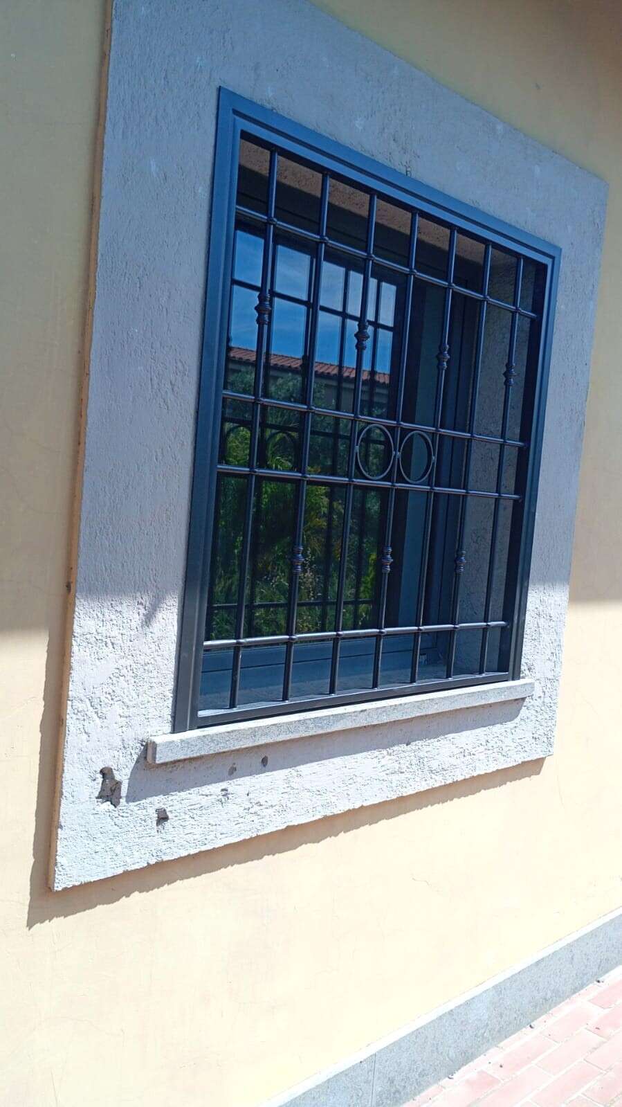 Grata di sicurezza blu scuro su una finestra con cornice in pietra, su una facciata gialla