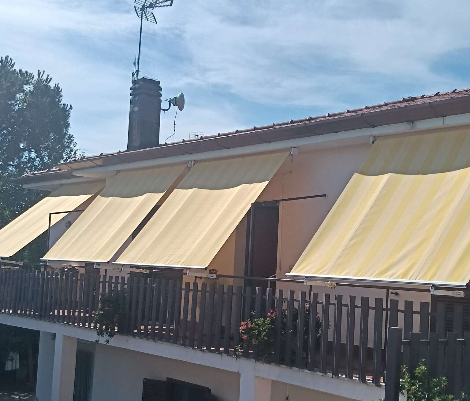 Tre tende da sole gialle sopra il terrazzo di una casa